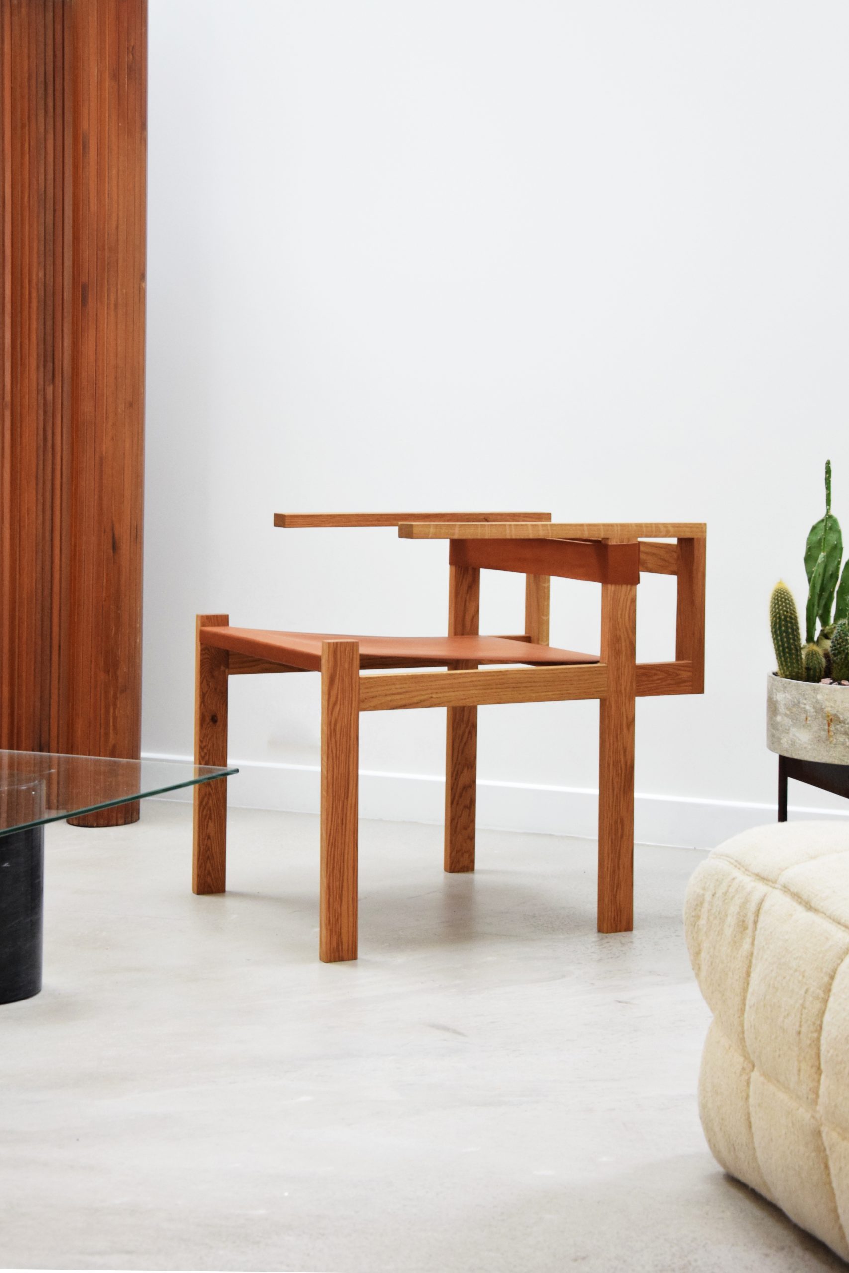 Vue d’une chaise en bois massif avec assise en cuir tendu, conçue sur mesure pour l’agence DVNA, dans un environnement intérieur moderne