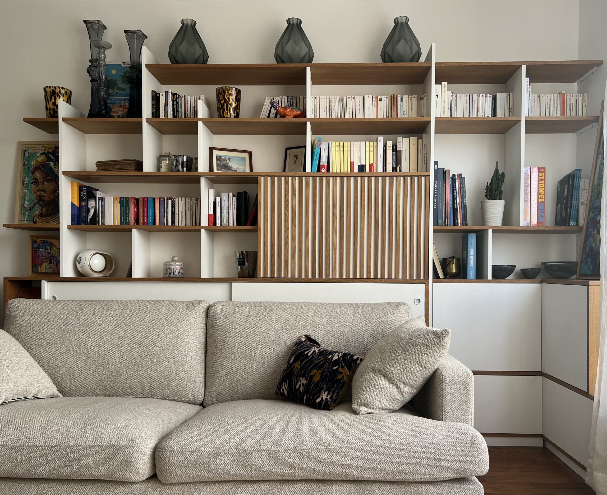 Réalisation d’une bibliothèque sur-mesure à Boulogne, alliant MDF peint, chêne massif et plaquage bois. Le meuble intègre un cache radiateur discret et un système coulissant en façade permettant de dissimuler la télévision. Certaines portes sont coulissantes, d'autres à ouvertures sans poignées "tip-on". Design sobre et fonctionnel adapté à un intérieur contemporain.
