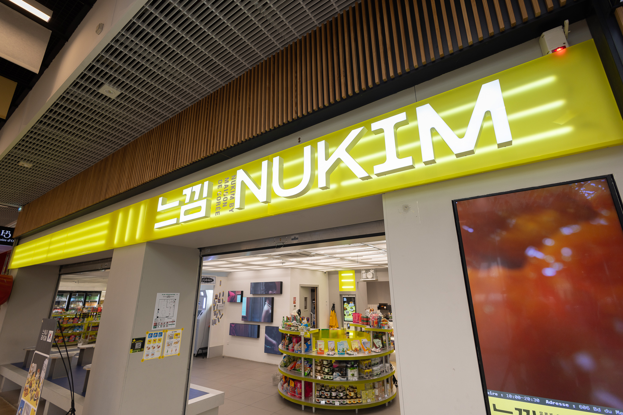 Vue du restaurant NUKIM à Nice : agencement complet avec enseigne lumineuse en plexi (pmma), mobilier sur mesure, présentoir arrondi, banquette en sky et bornes de commande lumineuses